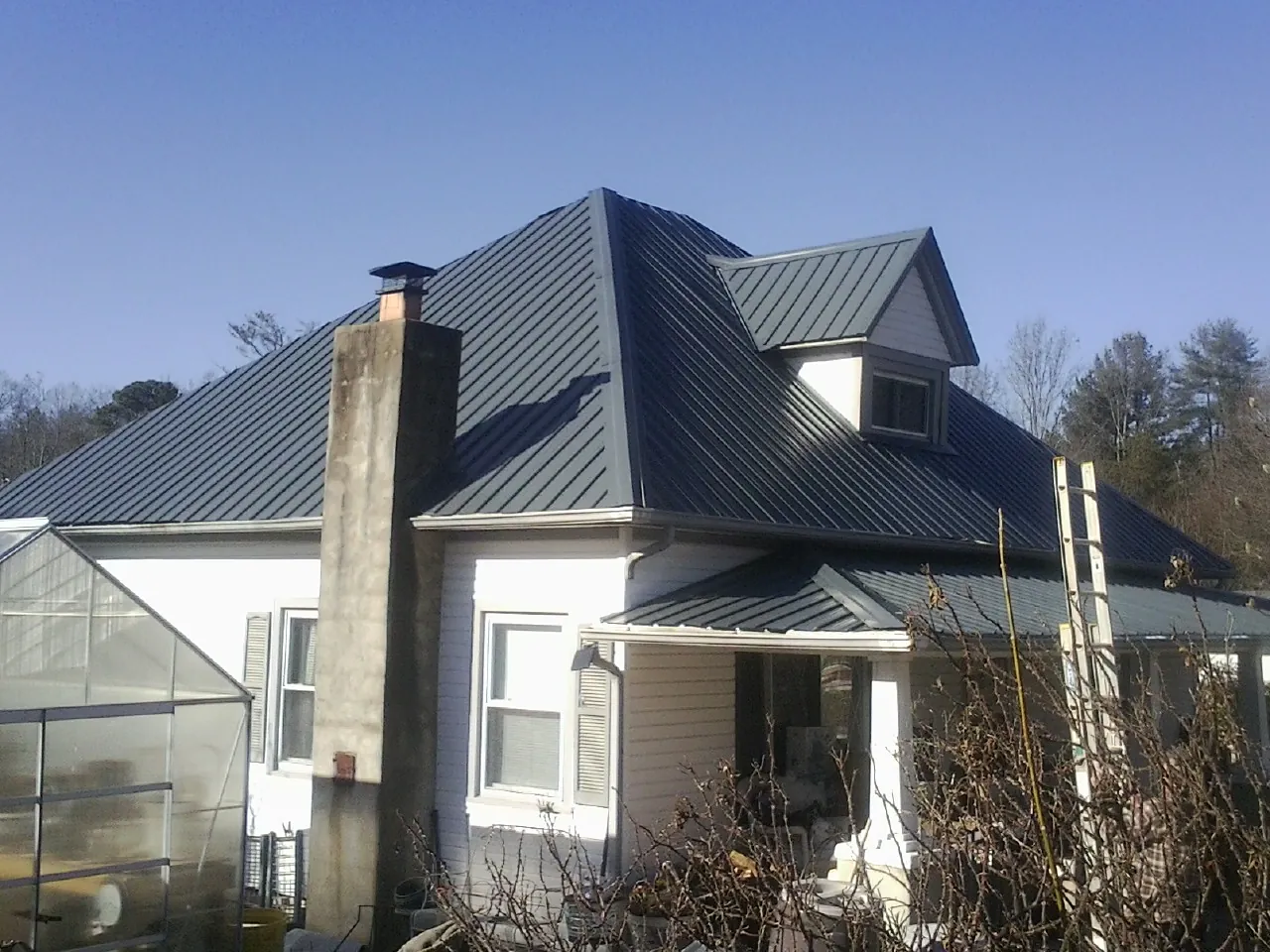 Dark blue standing seam metal roof on a white farmhouse with dormer in Foxboro