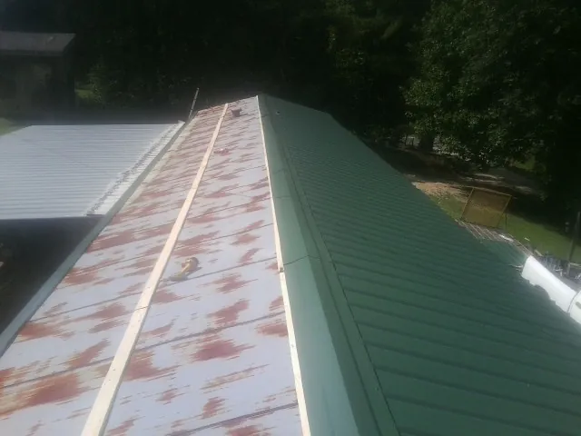 Old rusted panels beside newly installed green metal roofing — Wind Damage Roof Repair by Roofing Brothers in Foxboro