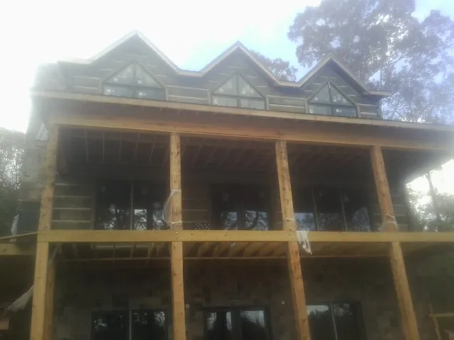 Dormers and porch framing on a large log home under construction — Roof Coating work by our crew in Foxboro