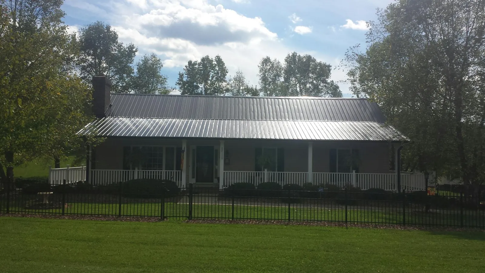 Gray metal roof on a brick ranch with a full width front porch — Gutter Guard Installation work by our crew in Foxboro