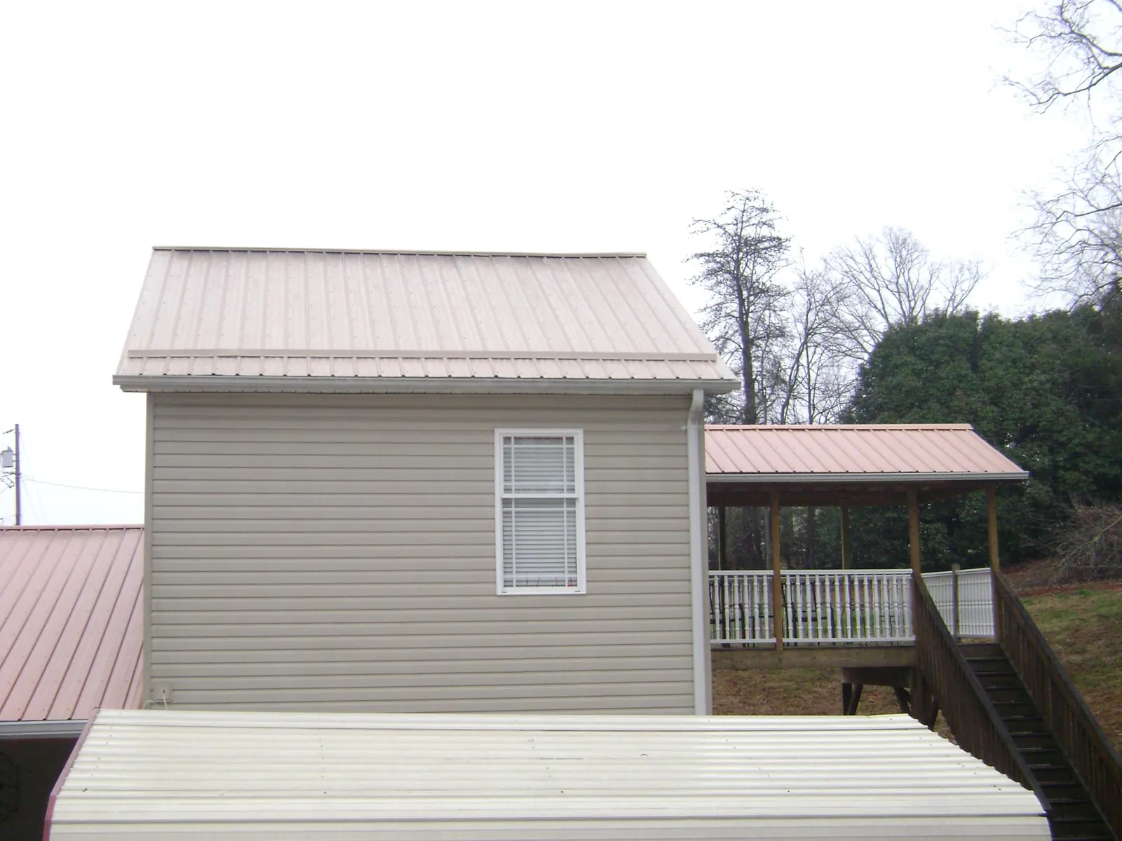 Tan metal roofs on a two story addition and attached porch, from a Roof Replacement job in Foxboro