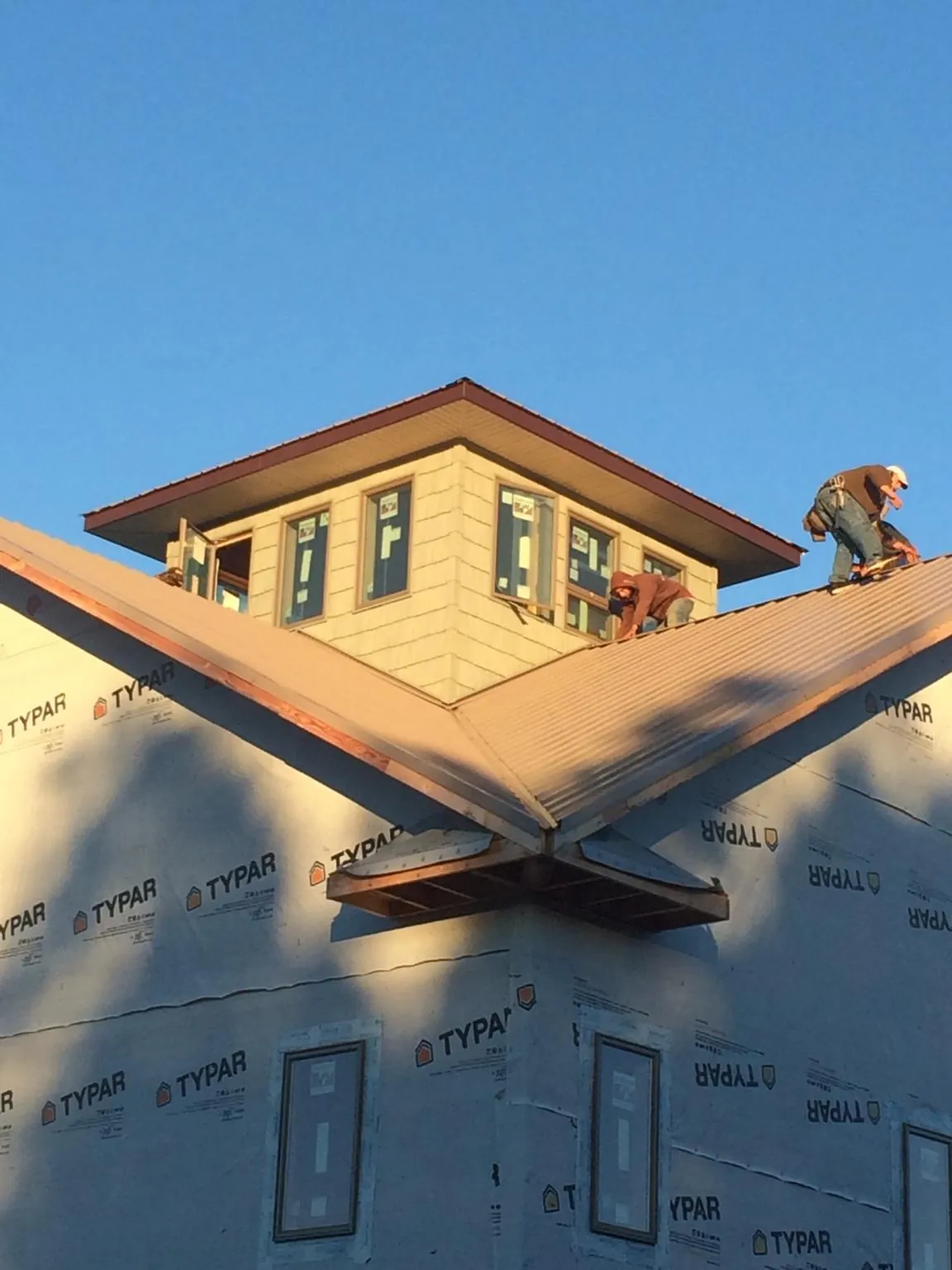 Roofers working around a rooftop cupola on a new metal roof at sunset — Roof Waterproofing in Foxboro by Roofing Brothers